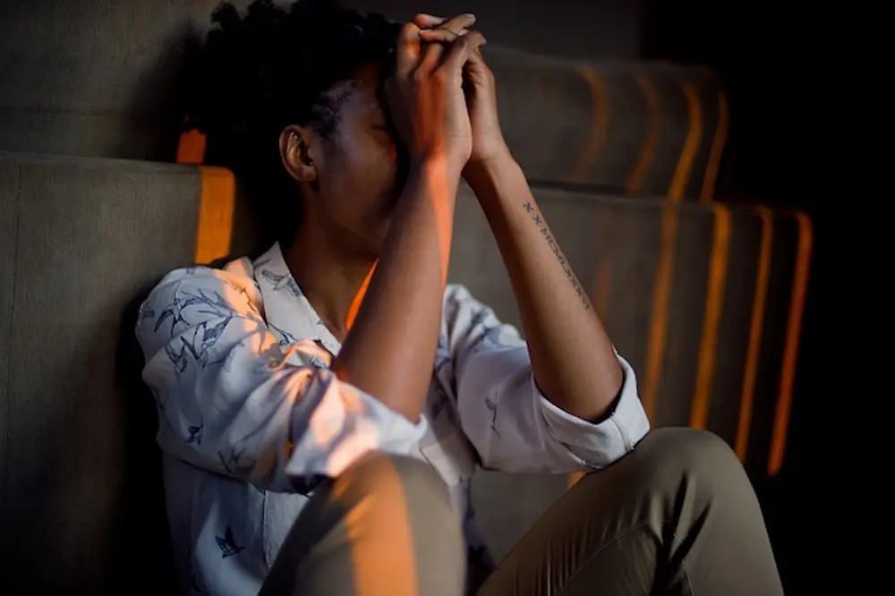 African woman in emotional distress, reflecting the quiet grief faced in customer care roles at health clinics in Kenya.